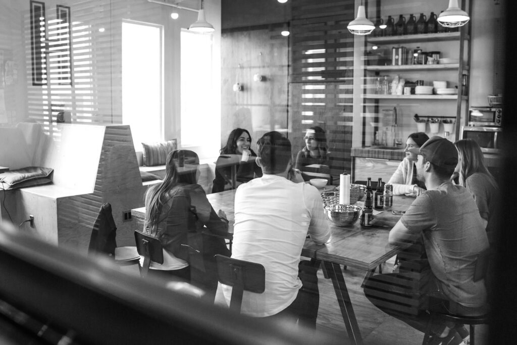 Equipe pequena reunida à mesa no próprio local de trabalho, conversando
