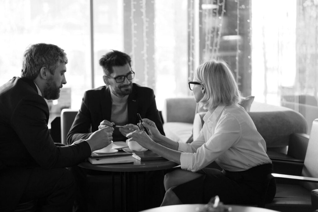 Três profissionais conversando sobre documentos em uma reunião à mesa